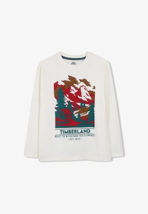 Wit shirt met lange mouwen met een rood, groen en bruin ontwerp van een berg, bomen en een hut, en Timberland-logo met slogan eronder.