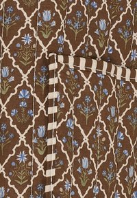 Vatteret stof med et brunt blomstermønster der har blå blomster og grønne blade, dækket med hvide og beige stribede kanter.