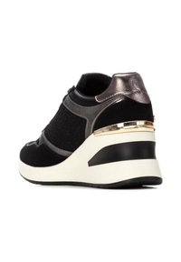 Sneaker nera con tacco a zeppa, caratterizzata da una combinazione di suede e texture metalliche, con un accento dorato sul retro. Punta arrotondata e collo imbottito.