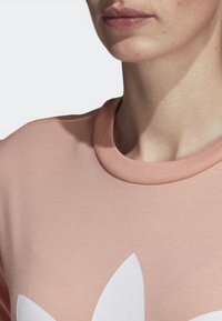 Ljusrosa bomulls Sweatshirt med rund halsringning och en stor vit blommig grafisk design. Slät textur med ribbad detalj vid halsringningen.