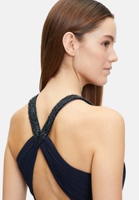 Námornícky šaty s komplikovanými beaded ramienkami, drapovaným dizajnom látky a otvoreným chrbtom. Hladká textura s priliehavou siluetou.
