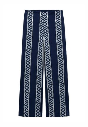 Brede broek in marineblauwe stof met verticale witte geometrische patronen en gestructureerde accenten langs de zijkanten. Ontwerp met elastische tailleband.