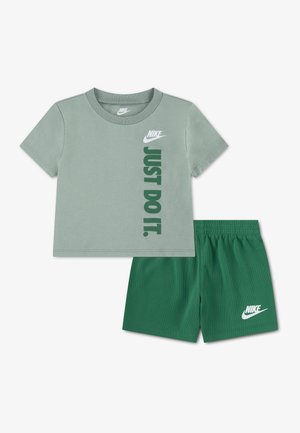 Camiseta verde de manga corta de Nike con el texto "JUST DO IT." y pantalones cortos verdes a juego con el logo de Nike en la pierna izquierda.