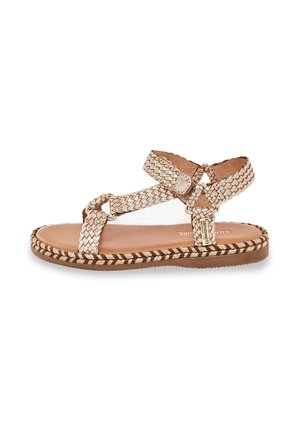 Geflochtene Ledersandalen in hellbeige mit flacher Sohle, die ein geflochtenes Design, Knöchelriemen und eine dekorative Schnalle in Goldton aufweisen.