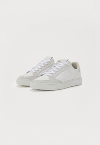 HVite sneakers med en glatt skinnøvre og suède detaljer, med flat såle, polstret krage og hvite snører. Minimalistisk design.