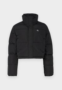 Čierna skrátená péřová bunda s vysokým golierom, prešitá textúra a zapínanie na zips. Obsahuje malé biele logo "CK" na ľavej hrudi.
