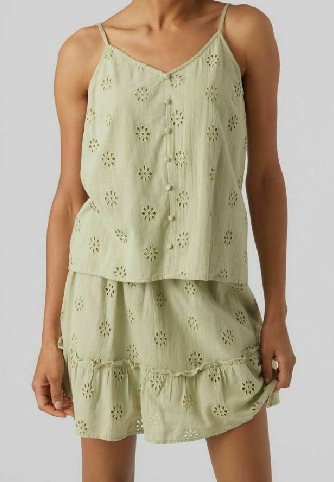 Ljusgrön ärmlös klänning med blommönster i hål, knäppning fram och lager av volangkant. Tillverkad av andningsbart material.