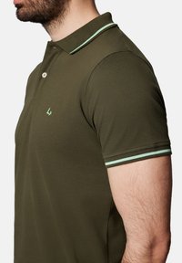 Oliwkowa koszulka polo o fakturowanym wykończeniu, z dwoma guzikami, miętowym kołnierzykiem i pasującymi akcentami na rękawach.