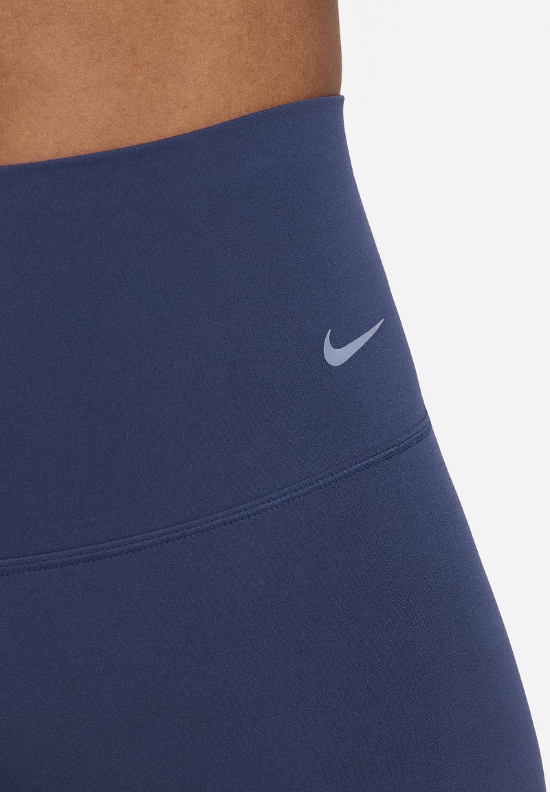 Marineblaue hochtaillierte Leggings aus dehnbarem Material, mit einem kleinen grauen Nike-Logo am Bund. Glatte Textur mit flachen Nähten.