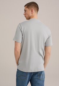 Hallikas lühikeste varrukatega t-särk sileda puuvillase materjaliga, ümmarguse kaelusega ja mugava lõikega. Lihtne disain ilma logode või mustriteta.