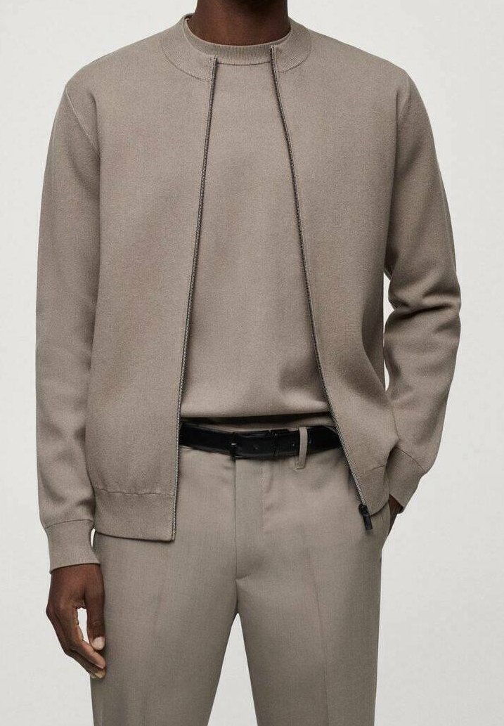 Light beige zip-up sweatshirt with a round neckline, textured fabric, and a slim fit, paired with matching trousers and a black belt.