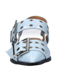 Helleblaue Lacklederschuhe mit zwei breiten Riemen, silbernem Beschlag, dekorativen Ösen und einem offenen Design. Flache, abgerundete Zehen.