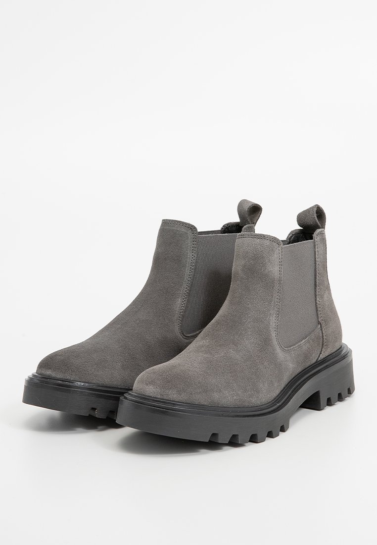 Stivaletti alla caviglia in suede grigio con pannelli elastici sui lati, un linguetta per il pullo e una suola in gomma nera chunky con un design scanalato.