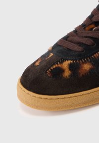 Brązowe zamszowe sneakersy z akcentami w panterkę, z gumową podeszwą i ciemnymi sznurowadłami. Okrągły kształt czubka z teksturowanymi detalami.