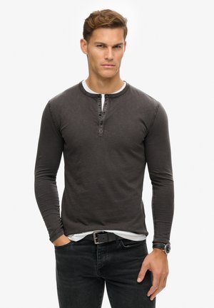 Camisa henley de manga larga en gris carbón, mezcla de algodón, con una tapeta de botones, cuello interior blanco en contraste y diseño ajustado.