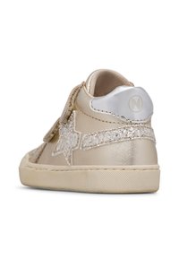 Zlaté tenisky s třpytivým hvězdným akcentem, texturovaným svrškem, suchým zipem, hladkým špičkovým krytem a pevným gumovým podešvem.