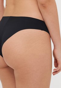Black bikini bottoms featuring a simple design, smooth texture, and a low-rise cut, with stitching detail along the edges.