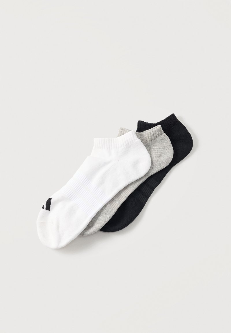 Drei Paar Knöchelsocken in Weiß, Grau und Schwarz, diagonal auf einem hellen Hintergrund gestapelt.