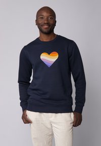 Marineblaues Sweatshirt mit einer mehrfarbigen Herzgrafik in Orange, Gelb, Creme, Lila und Lavendelstreifen. Weiche Textur, Rundhalsausschnitt.