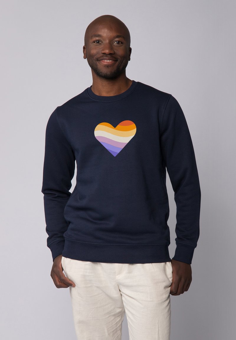 Marineblaues Sweatshirt mit einer mehrfarbigen Herzgrafik in Orange, Gelb, Creme, Lila und Lavendelstreifen. Weiche Textur, Rundhalsausschnitt.