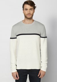 Maglione leggero a maniche lunghe in grigio e crema con texture a righe orizzontali e una striscia nera sul petto. Collo rotondo.