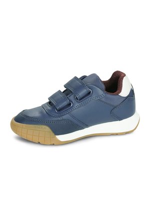 Basket enfant bleu marine avec deux bandes Velcro, accents blancs sur la semelle et le talon, et semelle extérieure en caoutchouc beige conçue pour jouer.