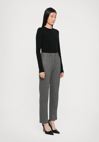 Black long-sleeve top paired with gray patterned trousers and black pointed-toe heels. Trousers feature an elastic waistband and straight legs.
