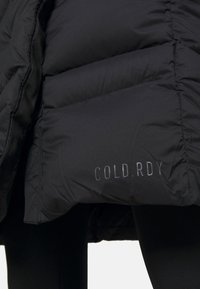 Svart pufferjacka med kviltad design som har "COLD.RDY"-logotyp i reflektivtryck på tyget. Slät textur och huva.