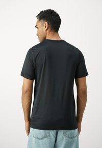 Must have mustal lühikese varrukaga T-särk, mis on valmistatud siledast kangast, klassikalise ümarika kaeluse ja vabalt istuva lõikega, koos helesiniste denim lühikeste pükste kombinatsiooniga.