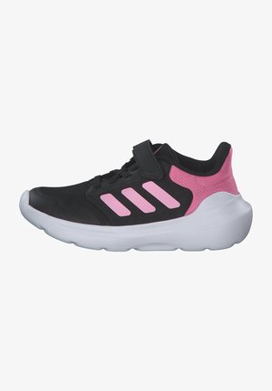 Zapato deportivo negro con acentos de malla rosa, que presenta tres rayas rosas, una correa de Velcro y una suela blanca acolchada.