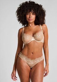 Beige lace bra and matching thong, featuring floral embroidery, underwire support, adjustable straps, and scalloped edges.