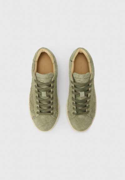 Αθλητικά παπούτσια από σουέτ σε ελιά πράσινο με χαμηλό προφίλ, διαθέτουν στρογγυλεμένη μύτη, σύστημα κορδονιών και μπεζ λαστιχένια σόλα.