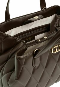 Borsa trapuntata marrone con finitura lucida. Presenta un interno spazioso, tasca con zip e dettagli in metallo color oro. Foderata con tessuto chiaro.