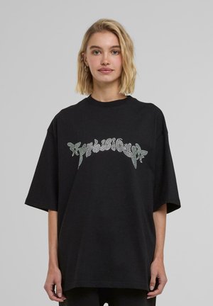 T-shirt noir surdimensionné en coton, arborant un imprimé en strass brillant avec un texte stylisé sur la poitrine. Manches courtes et col rond.