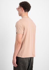 Lys beige kort�ærmet t-shirt med rund halsudskæring. Blødt stof, afslappet pasform, med et lille logo på venstre ærme.