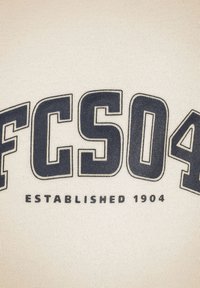 Tessuto bianco con testo blu navy audace, che recita "FC504" con "ISTITUITO NEL 1904" sottostante. Il testo ha un aspetto leggermente testurizzato.