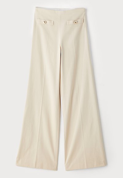 Beige weite Hosen mit hoher Taille, ausgestattet mit zwei dekorativen Fronttaschen und goldfarbenen Knöpfen auf jeder Seite. Glatte Stofftextur.