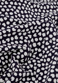 Navy Stoff mit weißen Druckmustern, einschließlich Herzen, Punkten und floralen Formen; glatte Textur mit einem weichen Fall.