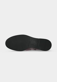 Semelle de chaussure en cuir noir avec une surface lisse et des détails en relief sur la pointure et le matériau au centre.