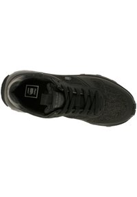 Svart sportskor med en strukturerad ovandel med nätdesign, snörningssystem och en robust gummisula. Logotyp synlig på tungdelen.