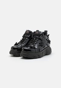 Black patent leather sneakers with textured accents, chunky sole, prominent lacing system, and butterfly detailing on the sides.