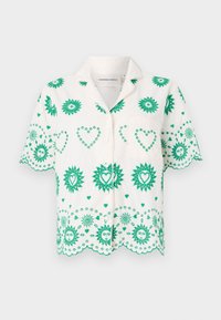 Korte mouwen shirt van witte stof, versierd met groene zon- en hartpatronen, met een kraag en een klein borstzakje.