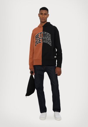 Hættetrøje med et delt design i sort og brunt, hvor "BETTER 2GETHER" er trykt i hvid. Sæt den sammen med mørke jeans og hvide sneakers.