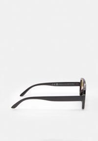 Lunettes de soleil rectangulaires noires avec finition brillante, branches larges et accents dorés sur la monture. Gravures intérieures clairement visibles. Design léger.