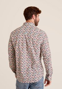 Lange mouw shirt met een kleurrijke bloemenprint op een lichte achtergrond, met een klassieke kraag en knoopsluiting aan de voorkant, gemaakt van lichte stof.