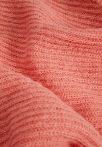 Tissu doux et texturé de couleur corail vif, présentant un motif côtelé avec une apparence chaude et pelucheuse. Idéal pour des vêtements ou accessoires confortables.