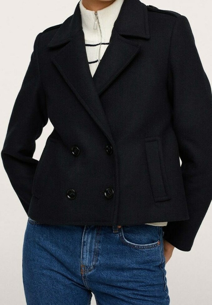 Cappotto doppiopetto blu navy realizzato in tessuto testurizzato, con grandi bottoni neri, ampie rever e un design accorciato.