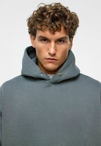 Grijze hoodie met een zachte, textuurstof, een ontspannen pasvorm en een trekkoordkap met decoratieve hardware accenten.