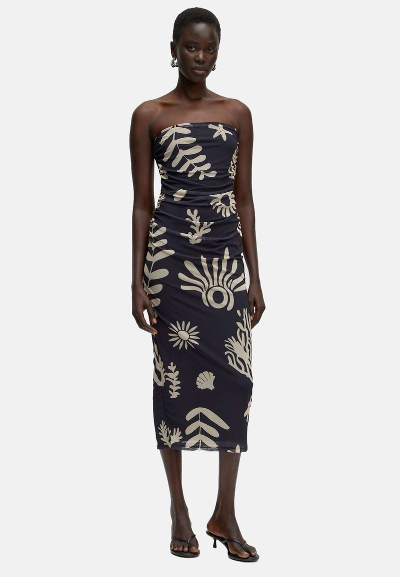 Marineblaues trägerloses Kleid mit beigen Blumen- und Blättermustern, das eine figurbetonte Silhouette und Raffungselemente aufweist.
