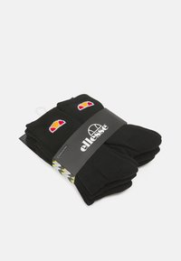 Schwarze Socken mit gerippter Struktur, versehen mit bunten Logo-Mustern und einer auffälligen schwarzen Verpackung mit gelben und grauen Akzenten.